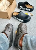 A pair of stylish clogs in black and grey marble finish, showcasing the brand's attention to detail and commitment to quality.