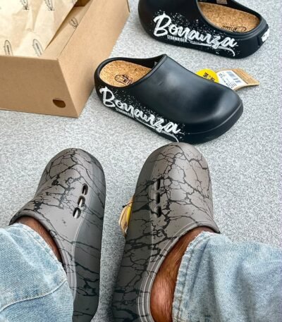 A pair of stylish clogs in black and grey marble finish, showcasing the brand's attention to detail and commitment to quality.