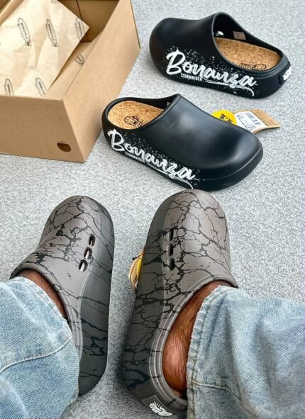 A pair of stylish clogs in black and grey marble finish, showcasing the brand's attention to detail and commitment to quality.