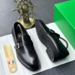 A pair of luxurious black leather loafers with a sleek design and sophisticated buckle, presented on a crisp white surface with a touch of Italian flair.