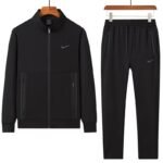 A luxurious Nike tracksuit comprising a zip-up jacket and matching joggers, both in dark grey with black accents, exuding sophistication and high-end athletic wear.