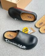 A pair of stylish clogs in black and grey marble finish, showcasing the brand's attention to detail and commitment to quality.