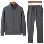 A luxurious Nike tracksuit comprising a zip-up jacket and matching joggers, both in dark grey with black accents, exuding sophistication and high-end athletic wear.