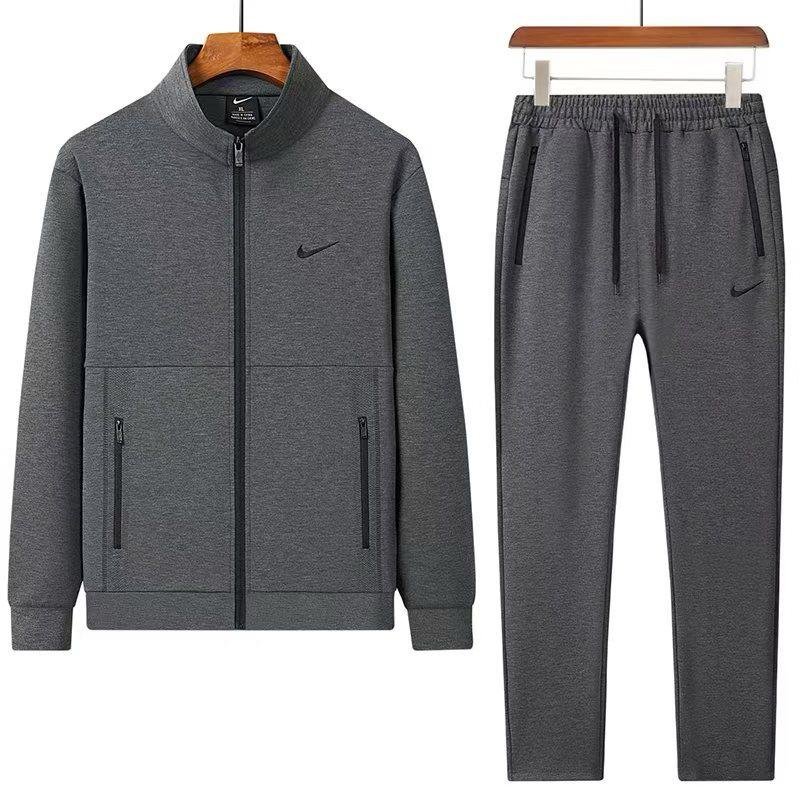 root A luxurious Nike tracksuit comprising a zip-up jacket and matching joggers, both in dark grey with black accents, exuding sophistication and high-end athletic wear.