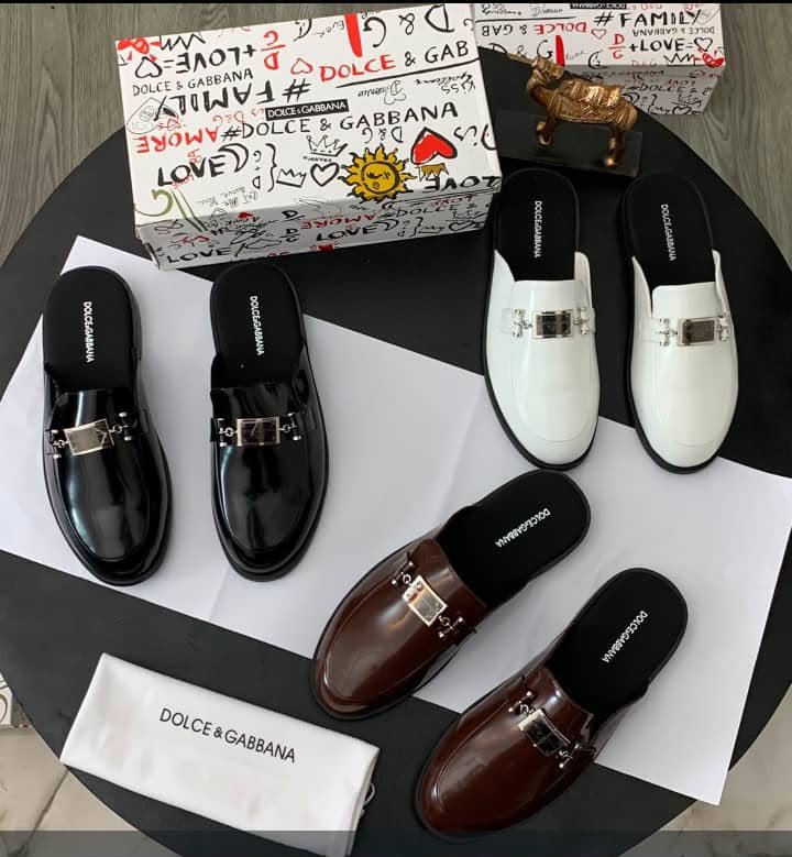 root A luxurious display of Dolce & Gabbana half shoes in black, brown, and white, accompanied by the brand's signature box and cloth.