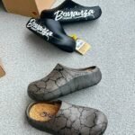 A pair of stylish clogs in black and grey marble finish, showcasing the brand's attention to detail and commitment to quality.