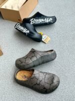 A pair of stylish clogs in black and grey marble finish, showcasing the brand's attention to detail and commitment to quality.