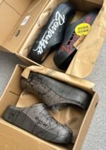A pair of stylish clogs in black and grey marble finish, showcasing the brand's attention to detail and commitment to quality.