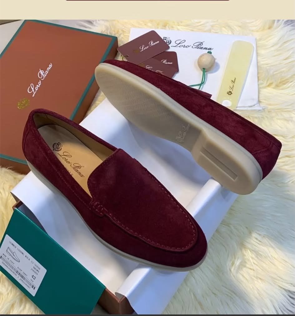 WhatsApp Image 2026-10-13 at 9.54.16 AM A pair of luxurious maroon loafers with velvety texture, displayed on a white shoe box with accessories and packaging in the background.